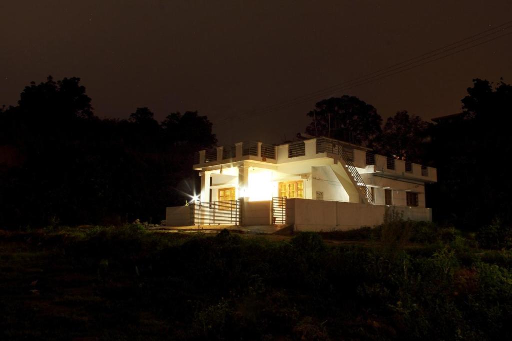 a white house with its lights on at night at Coorg Rahul Villa- 3 Deluxe Bedrooms in Madikeri