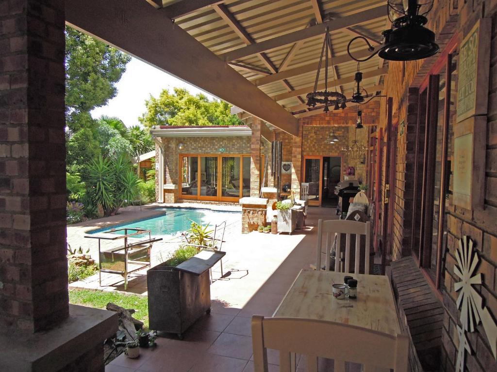 an outdoor patio with a table and chairs and a pool at Pumpkin Tree Guesthouse in Middelburg