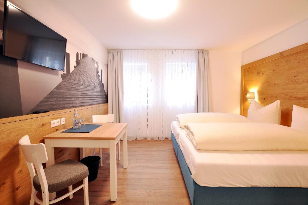 ein Hotelzimmer mit einem Bett, einem Tisch und einem Bett in der Unterkunft Gästehaus zur Krone in Waltenhofen