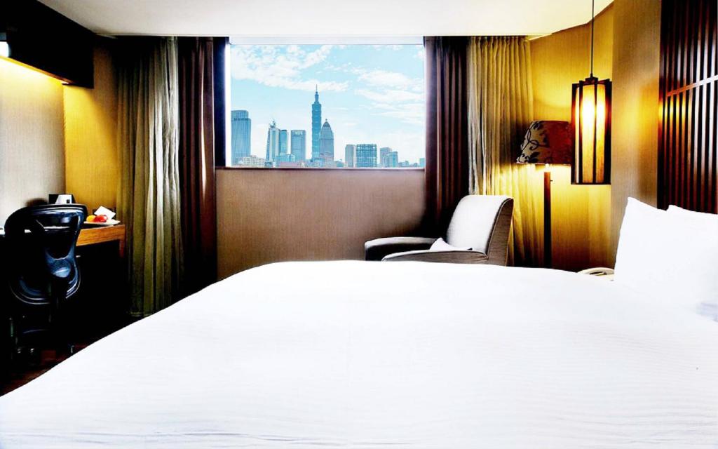 a hotel room with a large white bed and a window at Guide Hotel Taipei Bade in Taipei