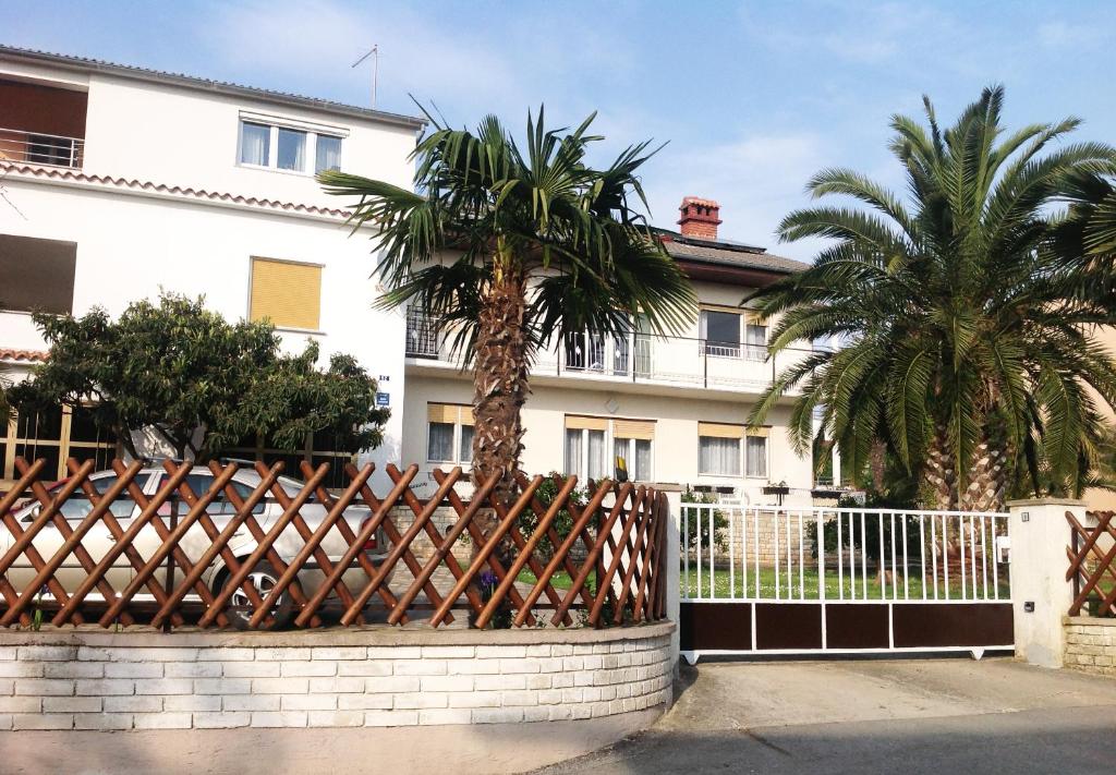 a fence with two palm trees in front of a building at Apartment Medulin in Medulin