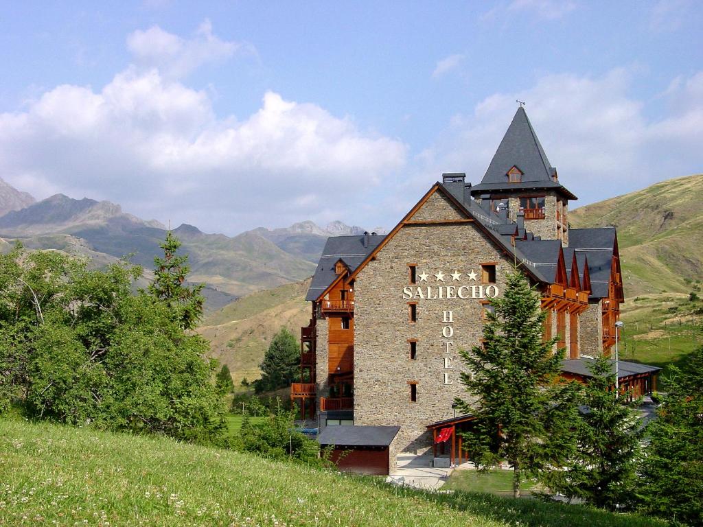 a building on a hill with mountains in the background at Hotel Saliecho in Formigal