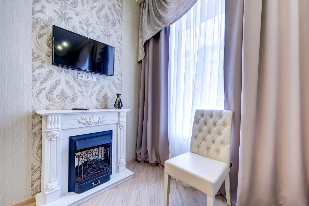 a living room with a fireplace and a white chair at Guest rooms on Marata 10 in Saint Petersburg