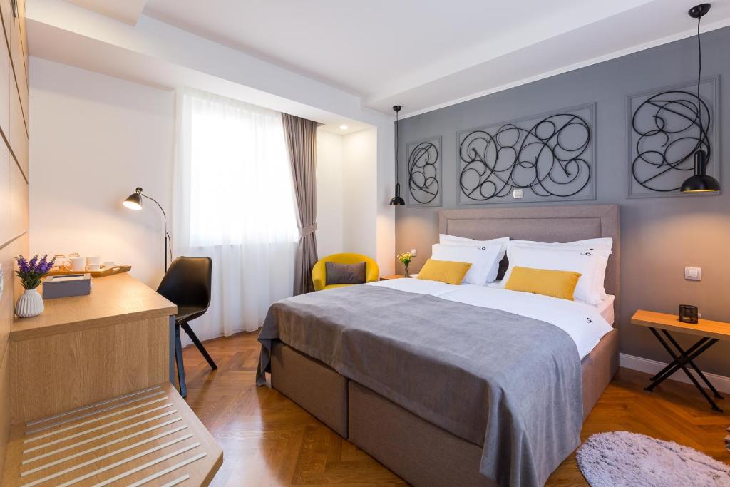 ein Hotelzimmer mit einem großen Bett und einem Schreibtisch in der Unterkunft The Well Luxury Rooms in Zadar