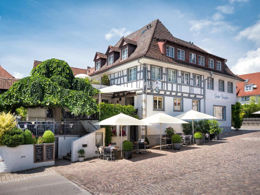 a large white building with umbrellas in front of it at Hotel Guter Tropfen in Hagnau