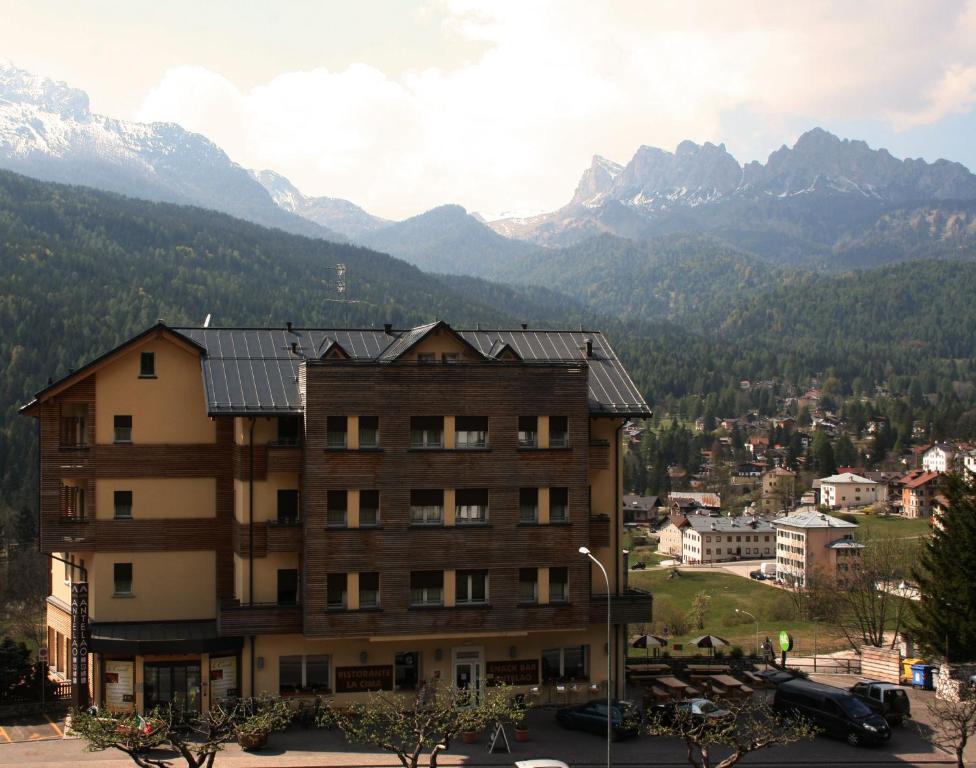 a building with mountains in the background at Antelao Dolomiti Mountain Resort in Borca di Cadore