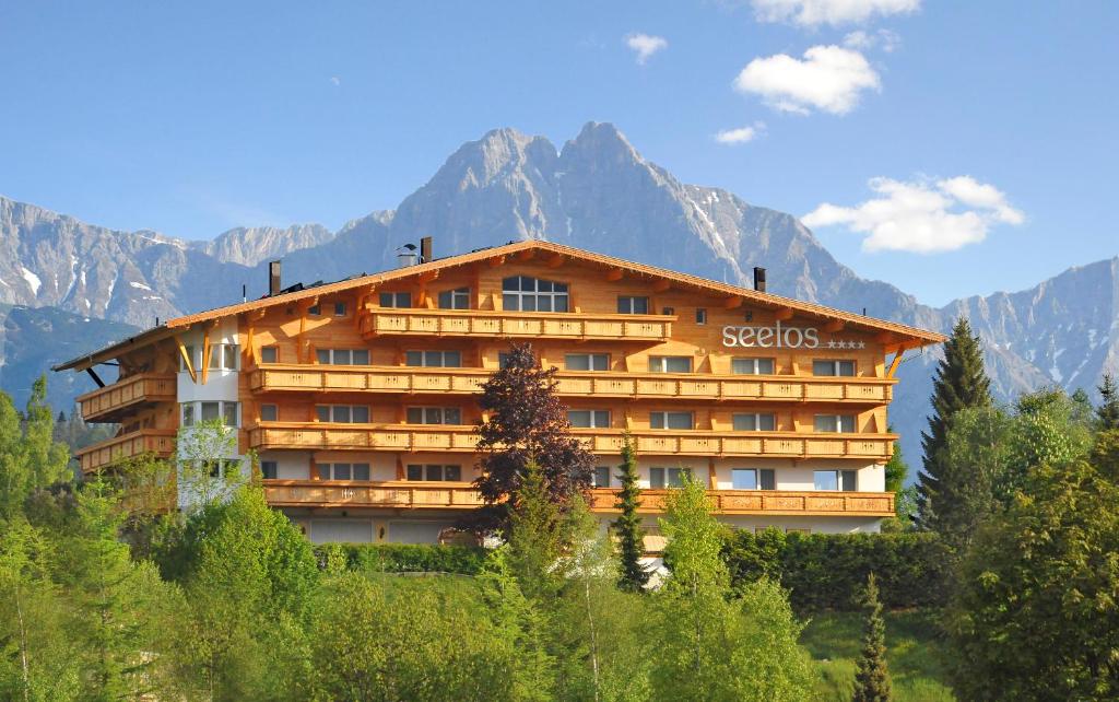 a building on a hill with mountains in the background at Hotel Seelos in Seefeld in Tirol