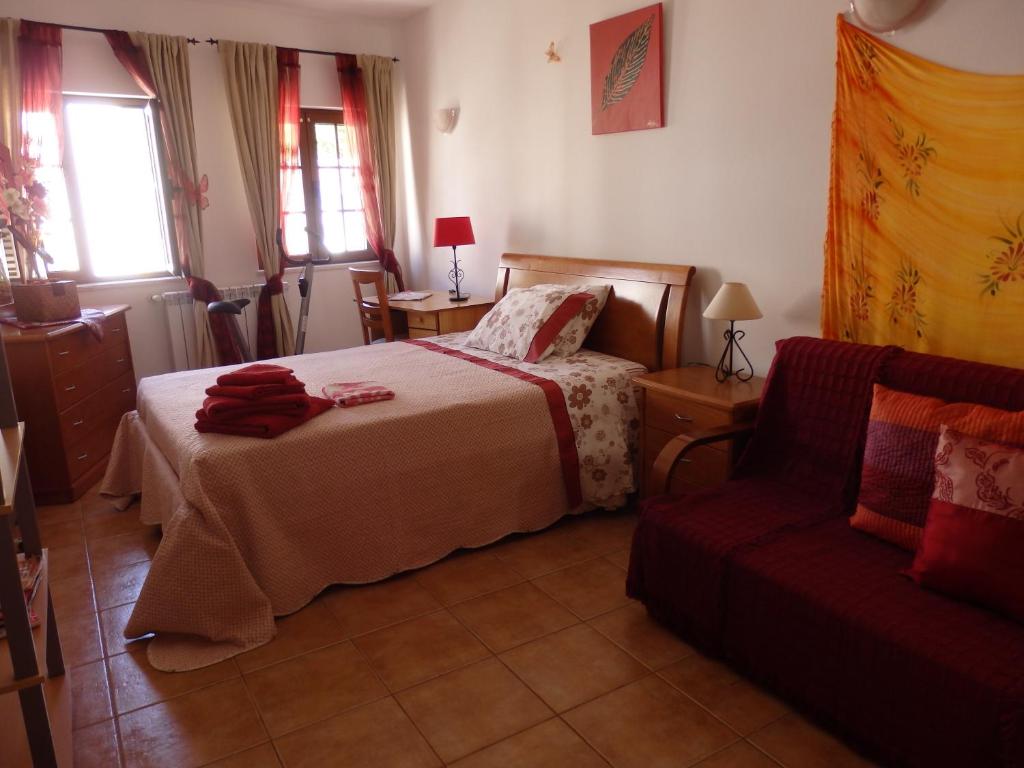 um quarto com uma cama e um sofá em Casa Riqueta Silva em Bordeira