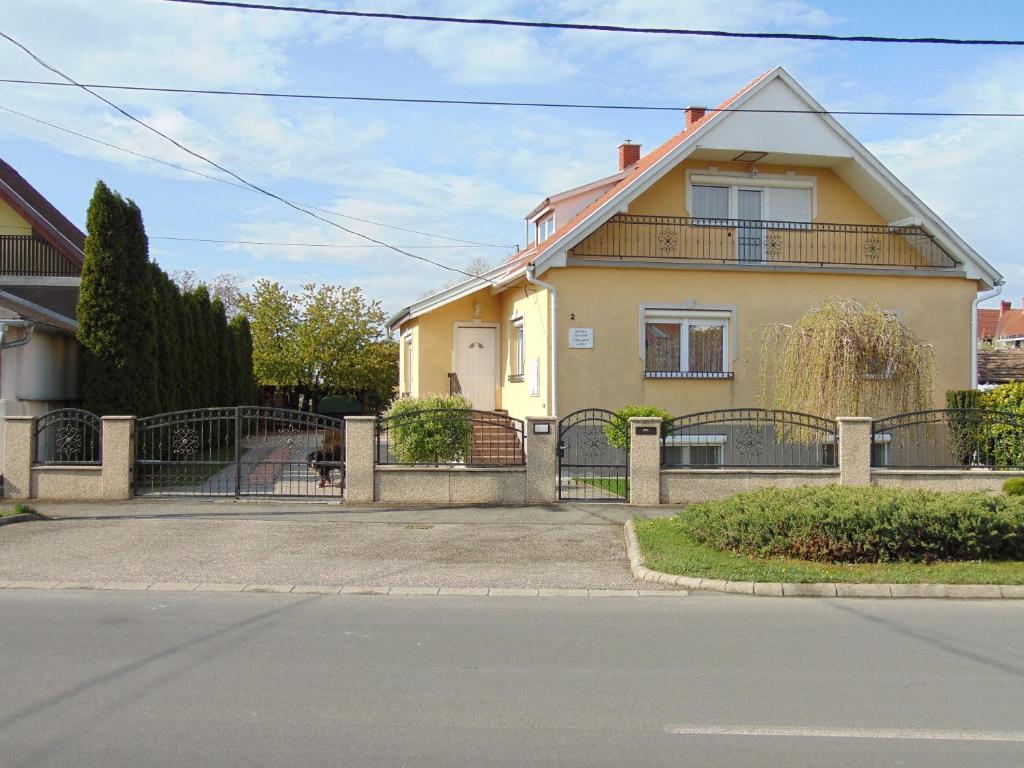 a house with a gate and a dog in front of it at Kata vendégház in Bük