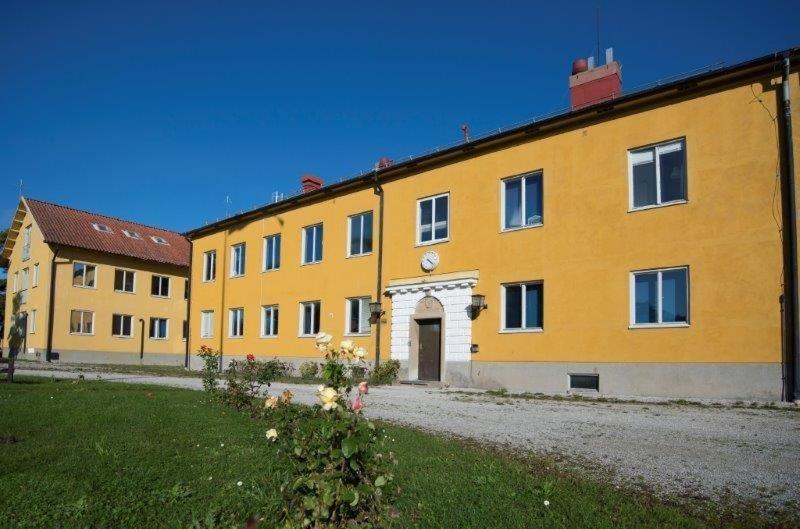 un gran edificio amarillo con una puerta en un patio en Östra Flygeln Bunge Vandrarhem en Fårösund