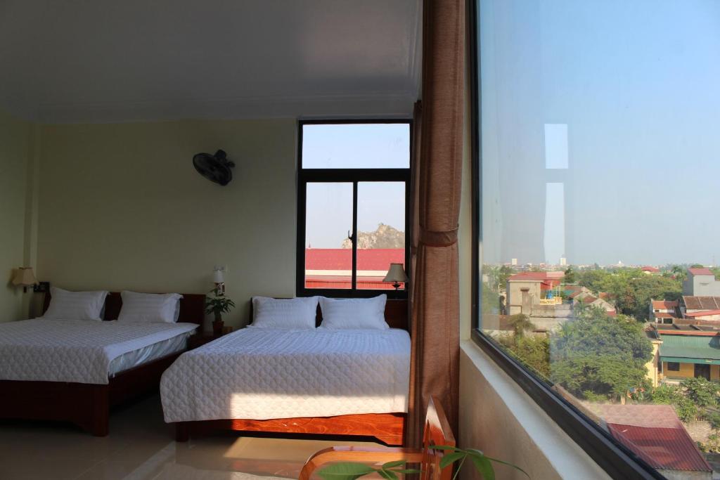 a bedroom with two beds and a large window at Sierra Homestay in Ninh Binh
