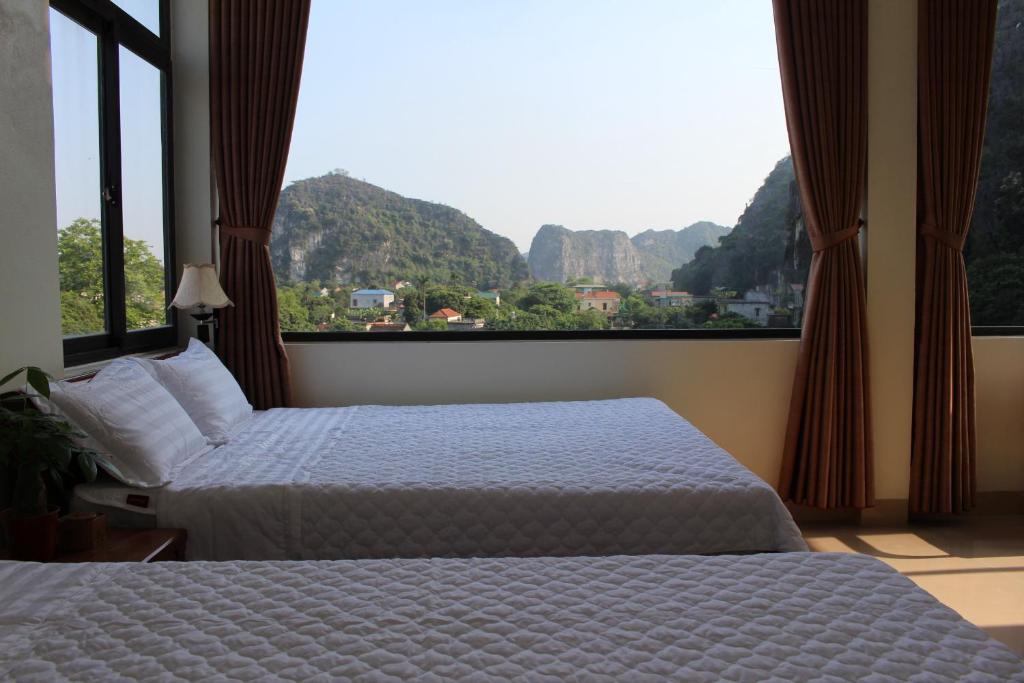 a bedroom with two beds and a large window at Sierra Homestay in Ninh Binh