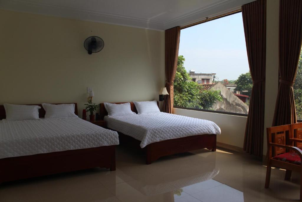 a bedroom with two beds and a large window at Sierra Homestay in Ninh Binh