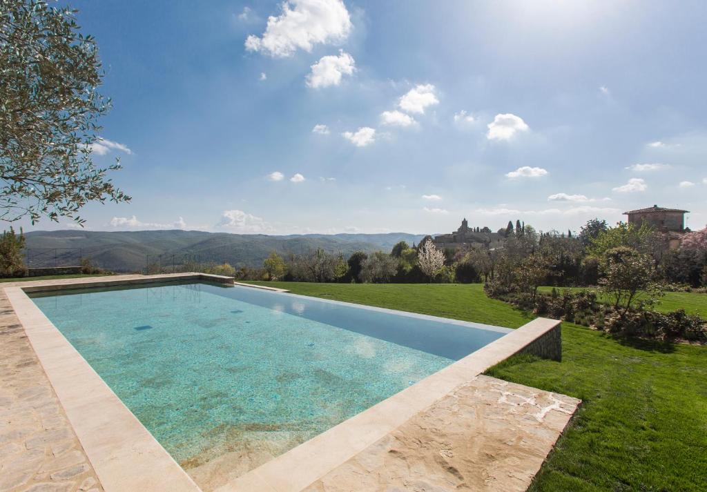 a swimming pool in a grassy yard with a view at Villa Le Barone in Panzano