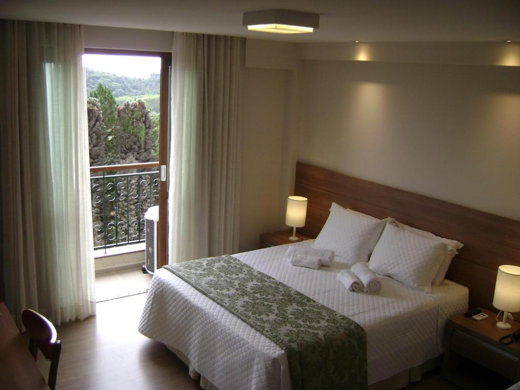 a hotel room with a bed and a large window at Flat Particular Pedra Azul in Pedra Azul