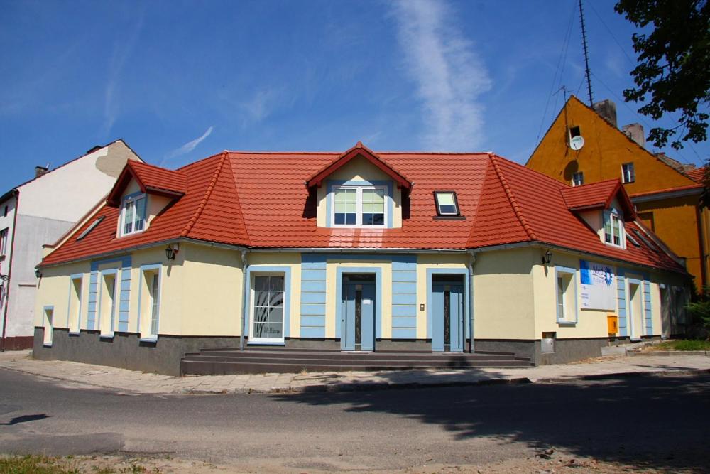 a house with a red roof on a street at Apartamenty Gościnne Med-Palace in Niemodlin