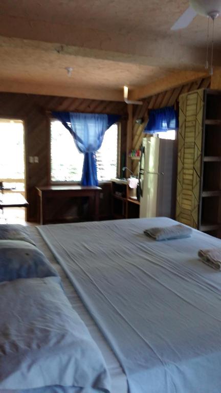 a large white bed in a room with a refrigerator at Apartments Chez Milady in Utila