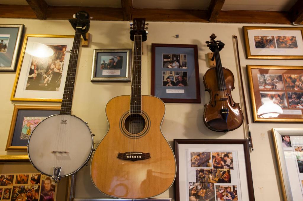 two acoustic guitars hanging on a wall with pictures at Port Charlotte Hotel in Port Charlotte