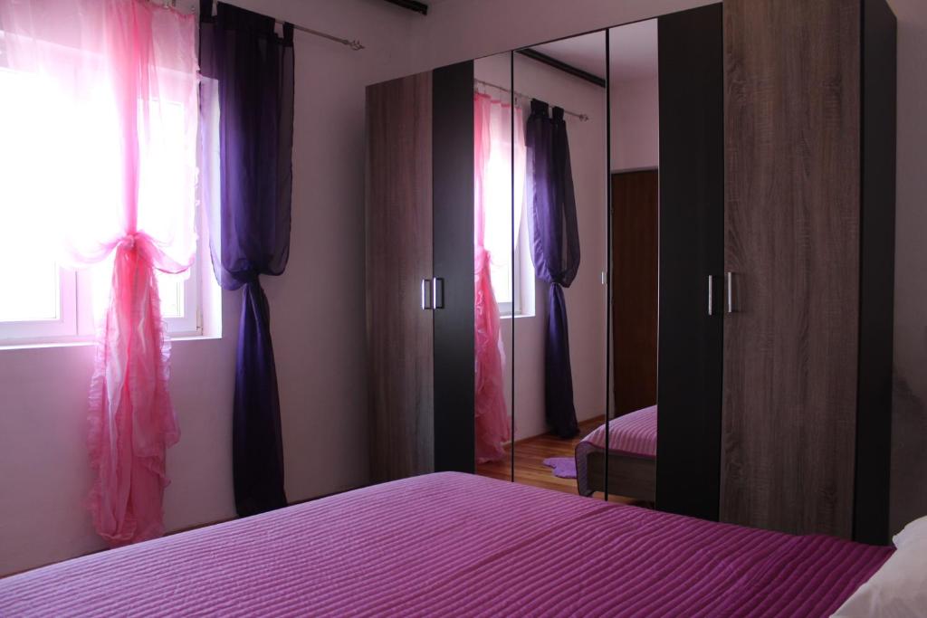a bedroom with a purple bed and a mirror at Petra Apartments in Korčula