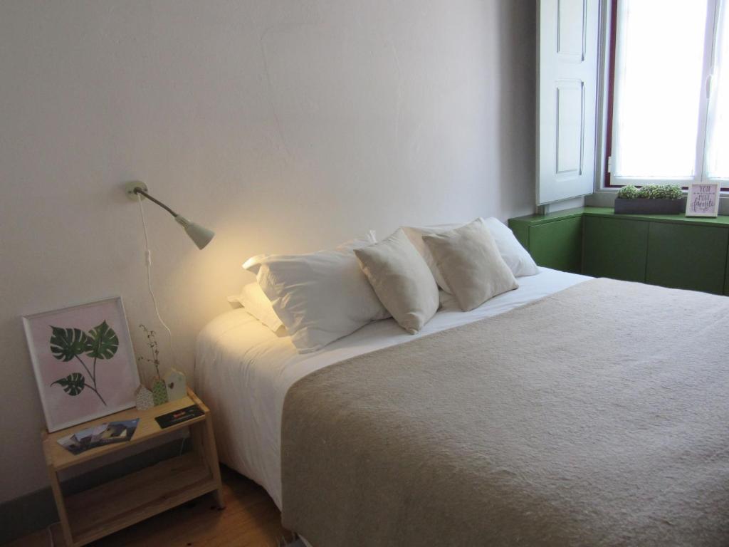 una camera da letto con un grande letto con lenzuola e cuscini bianchi di Most Art Boutique Hostel a Leiria