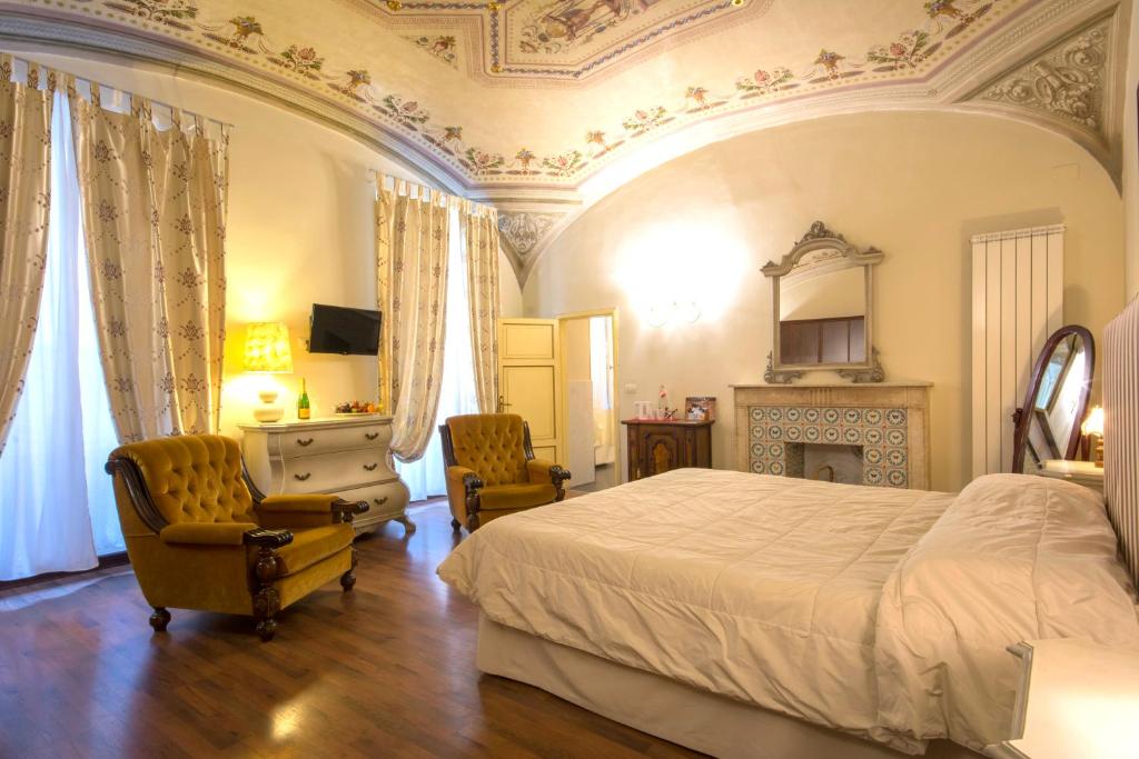 a bedroom with a bed and two chairs at B&B Pantaneto - Palazzo Bulgarini in Siena