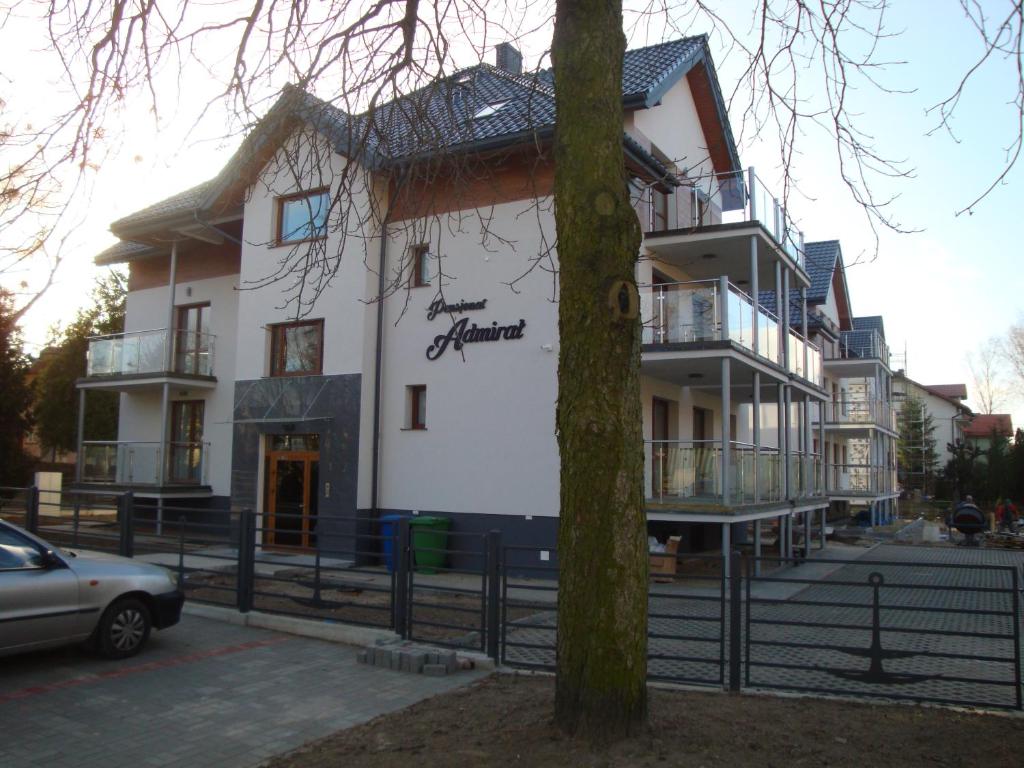 a white building with a tree in front of it at ApartHotel Admirał in Iława