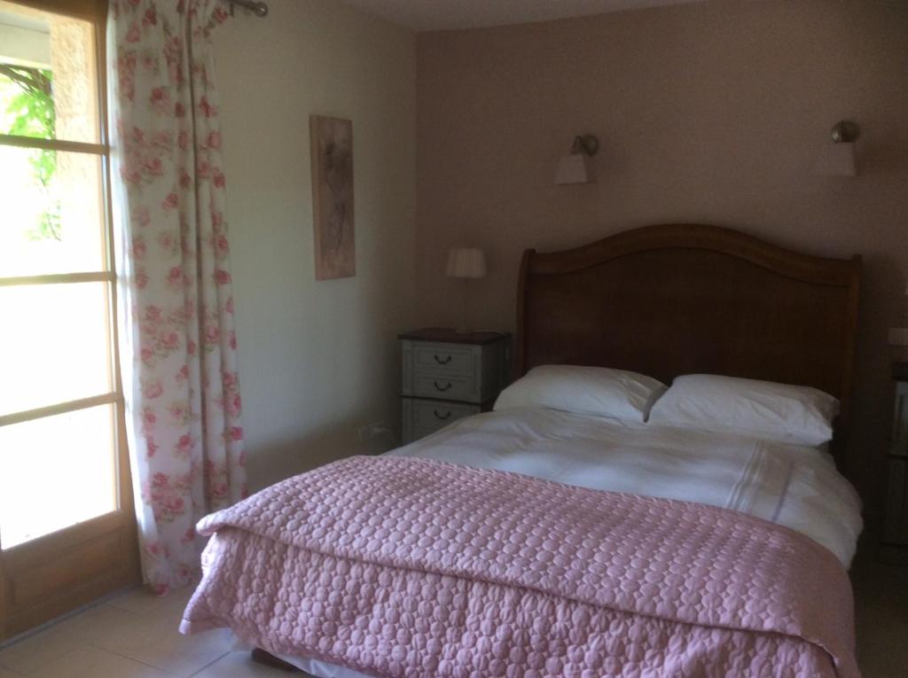 a bedroom with a bed with a pink blanket and a window at Les Jonquilles in Domme