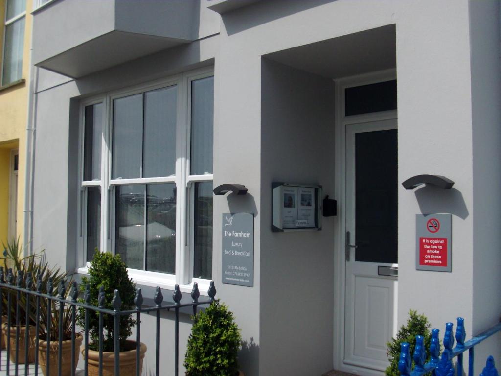 a white house with a door with a sign on it at Farnham Hotel in Tenby