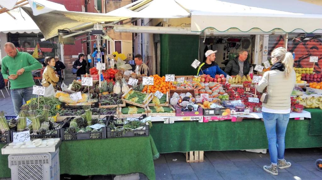 a group of people standing around a fruit and vegetable stand at Bacanal Apartment in Venice