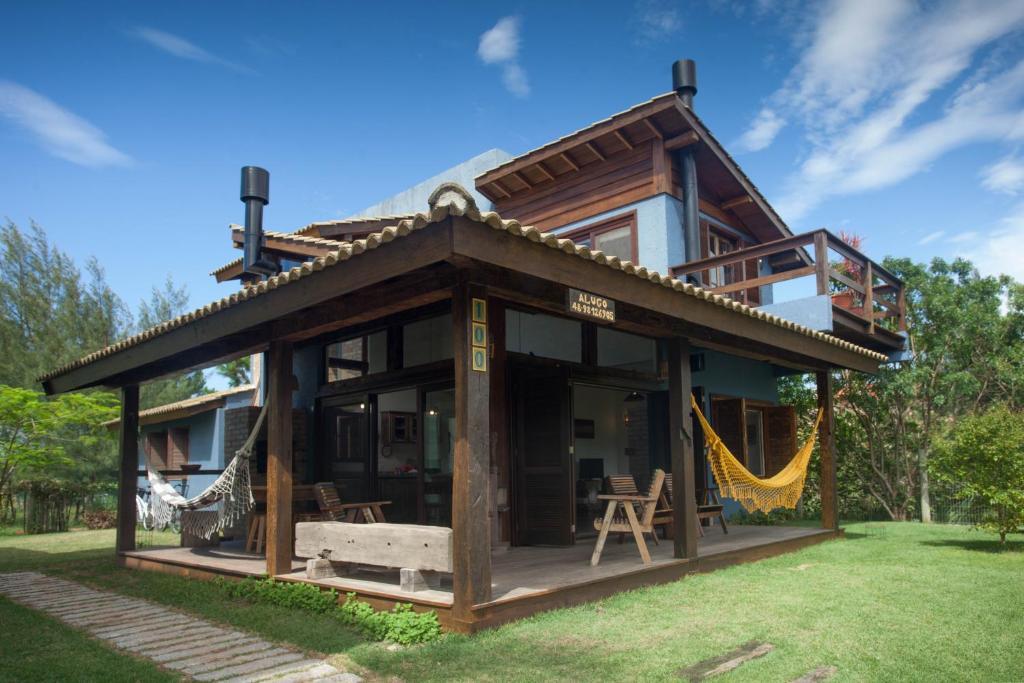 a log home with a hammock in the yard at Casa da Ferrugem in Garopaba