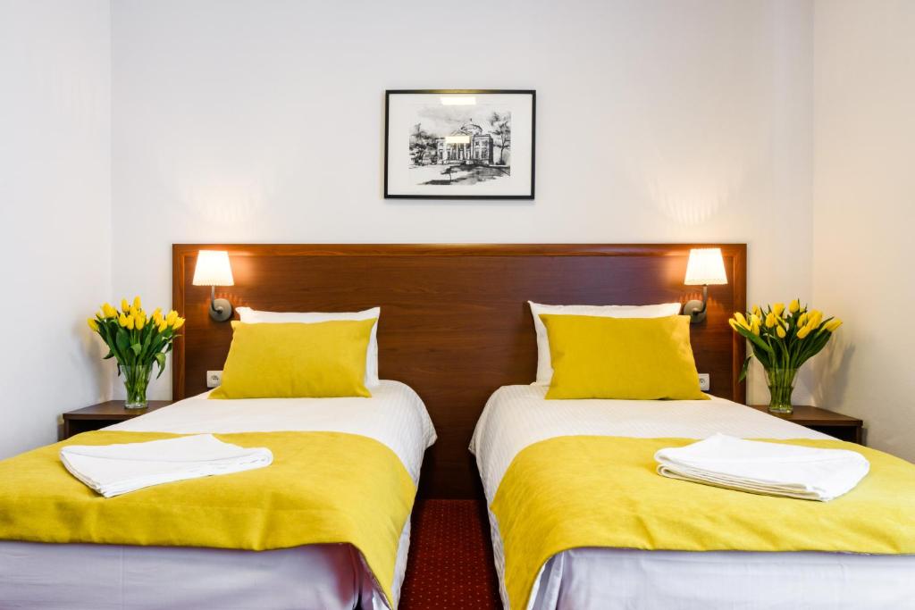 two beds in a room with yellow sheets and yellow pillows at L26 Łopuszańska in Warsaw
