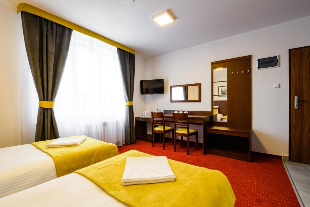 a hotel room with two beds and a desk at L26 Łopuszańska in Warsaw
