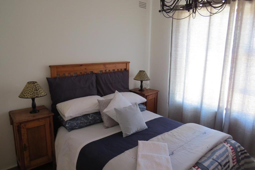 a bedroom with a large bed with white pillows at Chamomile Cottage 2 in Muizenberg
