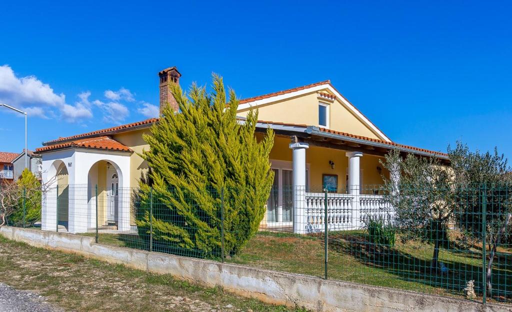 a yellow house with a fence in front of it at Holiday Home Vesna in Ližnjan