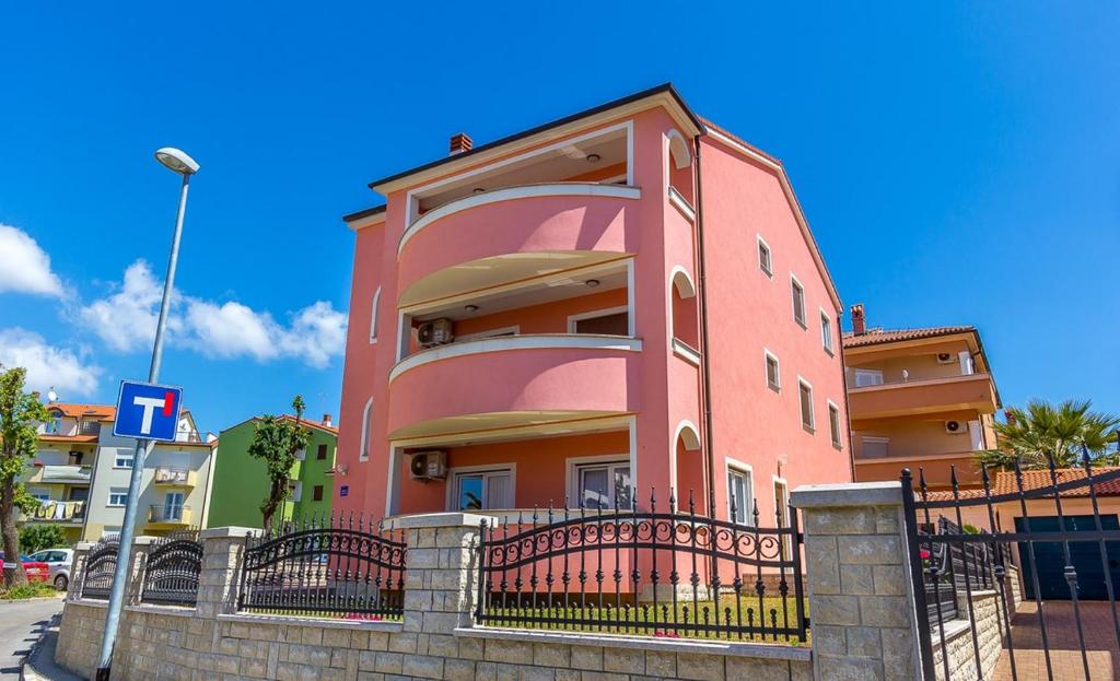 een roze gebouw met een hek ervoor bij Apartments Marich in Medulin
