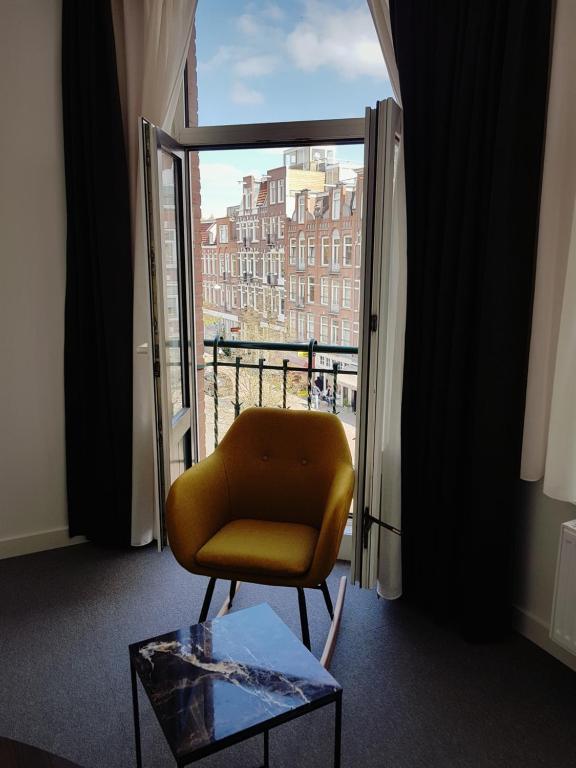 una silla amarilla sentada en una habitación con ventana en Hotel Heye 130, en Ámsterdam