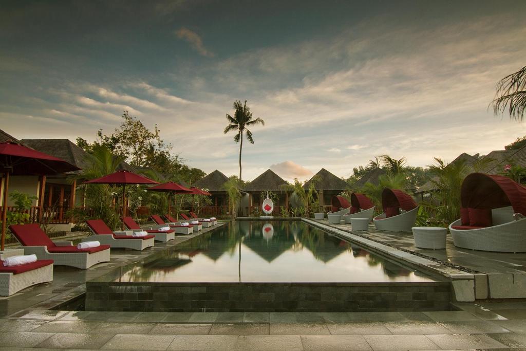 a pool at a resort with chairs and a palm tree at Samata Village Gili Air in Gili Islands