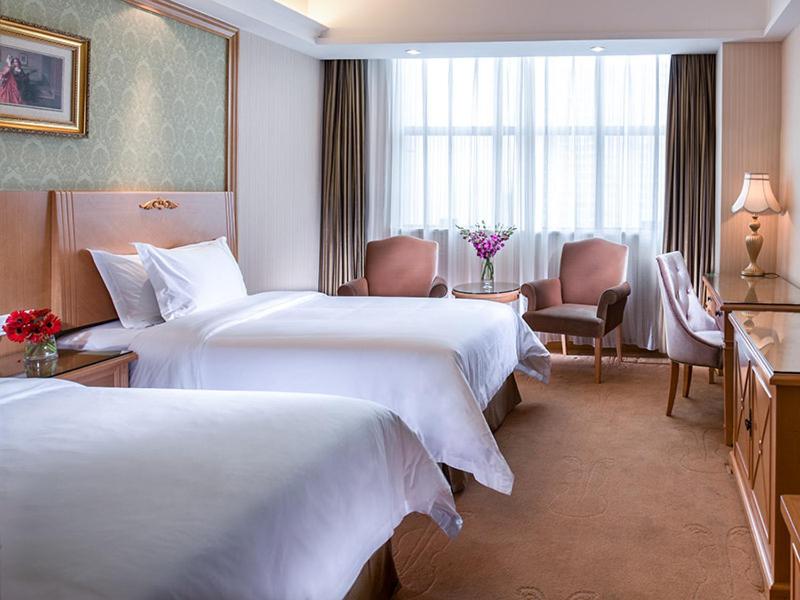 a hotel room with two beds and a window at Vienna International Hotel - Long Hua Wan Zhong Cheng Branch in Bao'an