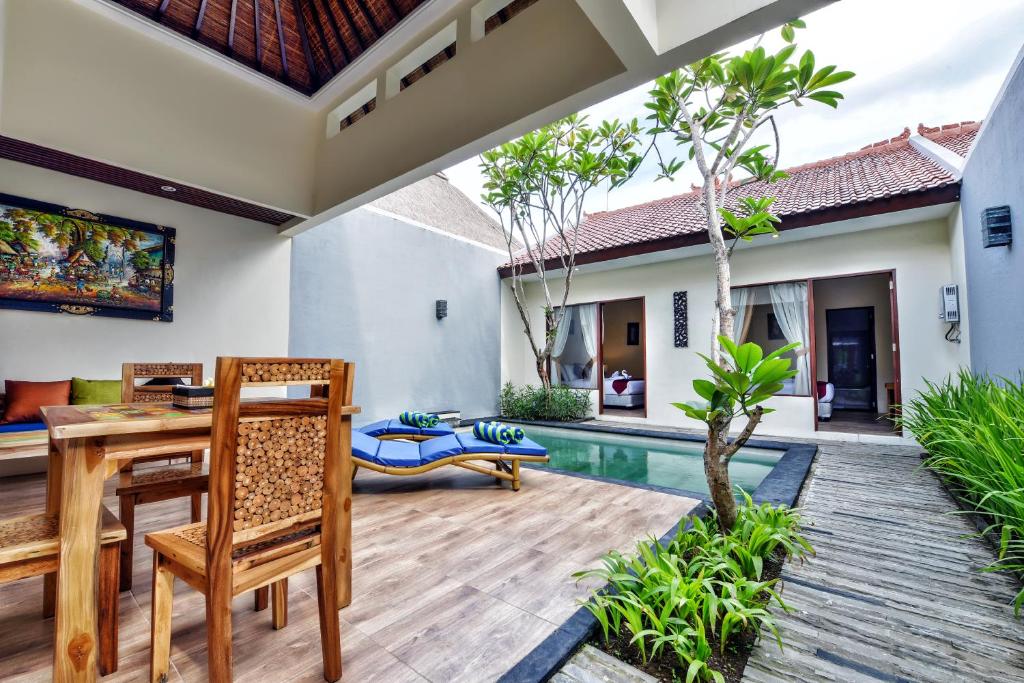 a patio with a table and chairs and a pool at Yoga Ubud Private Pool Villa in Ubud