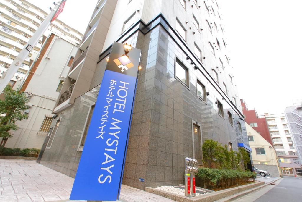 una señal azul frente a un edificio en HOTEL MYSTAYS Kamata, en Tokio