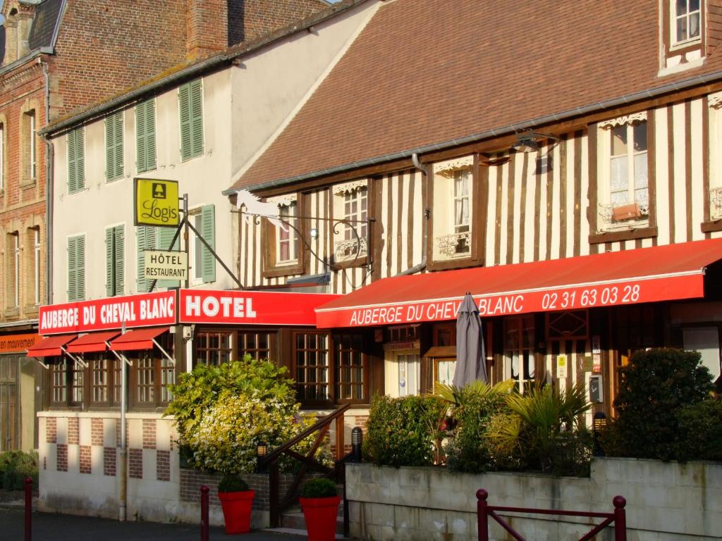 una fila de edificios con sombrillas rojas en una calle en Auberge Du Cheval Blanc, en Crèvecoeur-en-Auge