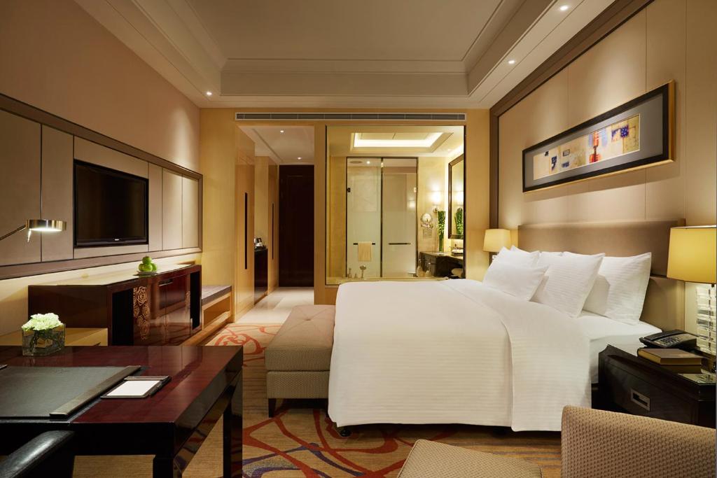 a bedroom with a large white bed and a living room at Wanda Realm Huaian in Huai'an
