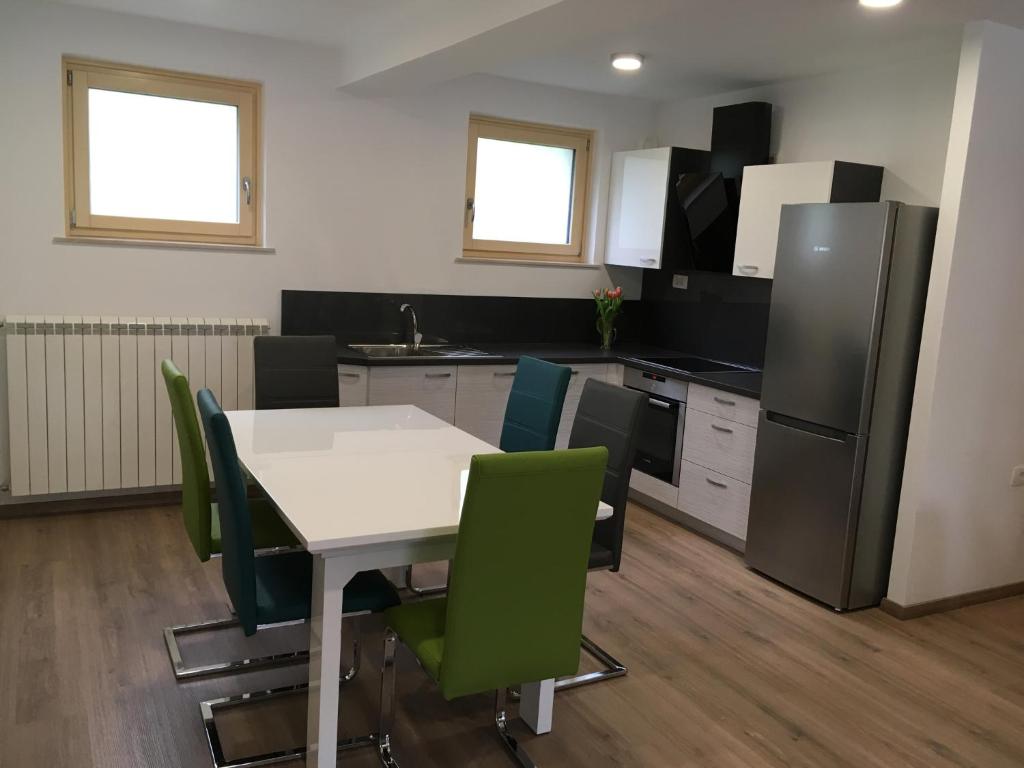 uma cozinha com uma mesa branca e cadeiras verdes em Apartment Lapanja em Slap ob Idrijci