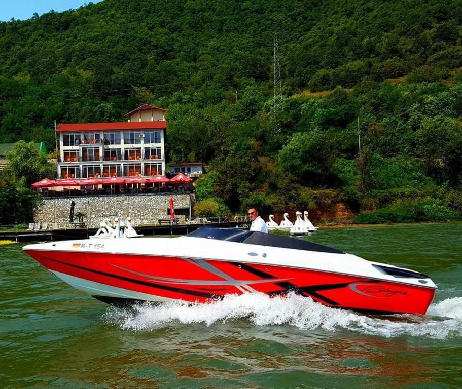 a red and white boat in the water at Pensiunea Decebal Resort - Cazanele Dunarii in Dubova