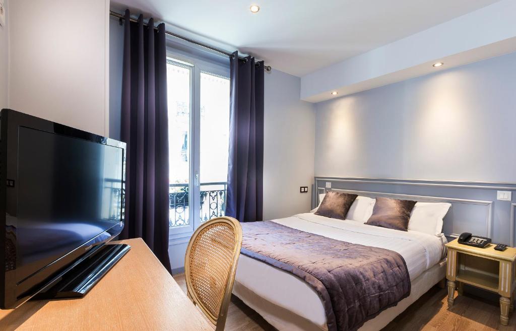 a bedroom with a bed and a flat screen tv at Hôtel Du Brésil in Paris