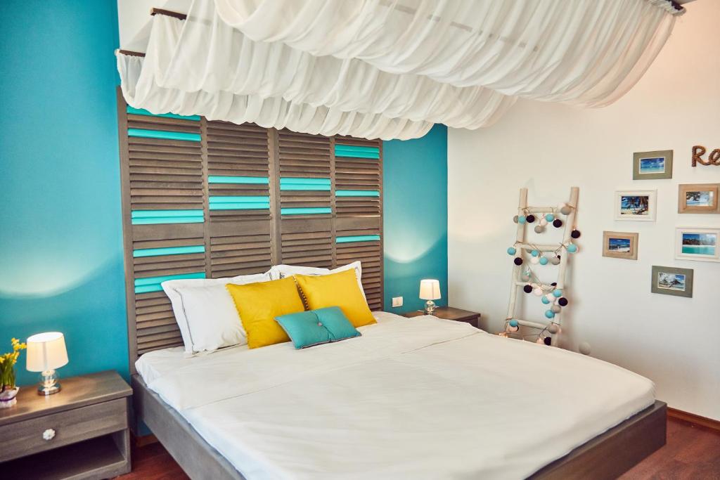 a bedroom with a large white bed with yellow and blue walls at Holidays Casa del Sole Mamaia Nord in Mamaia Sat/Năvodari