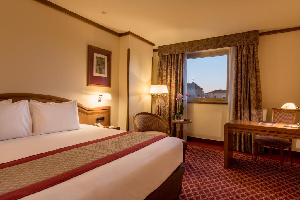 una camera d'albergo con letto, scrivania e finestra di Eurostars Las Claras a Salamanca