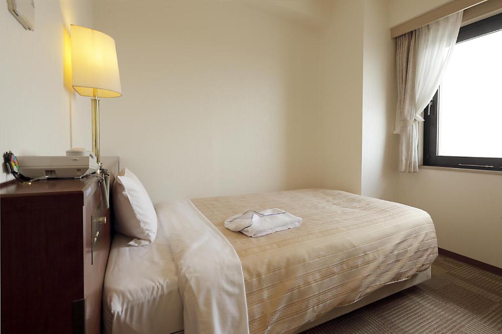 Postel nebo postele na pokoji v ubytování Kumegawa Wing Hotel