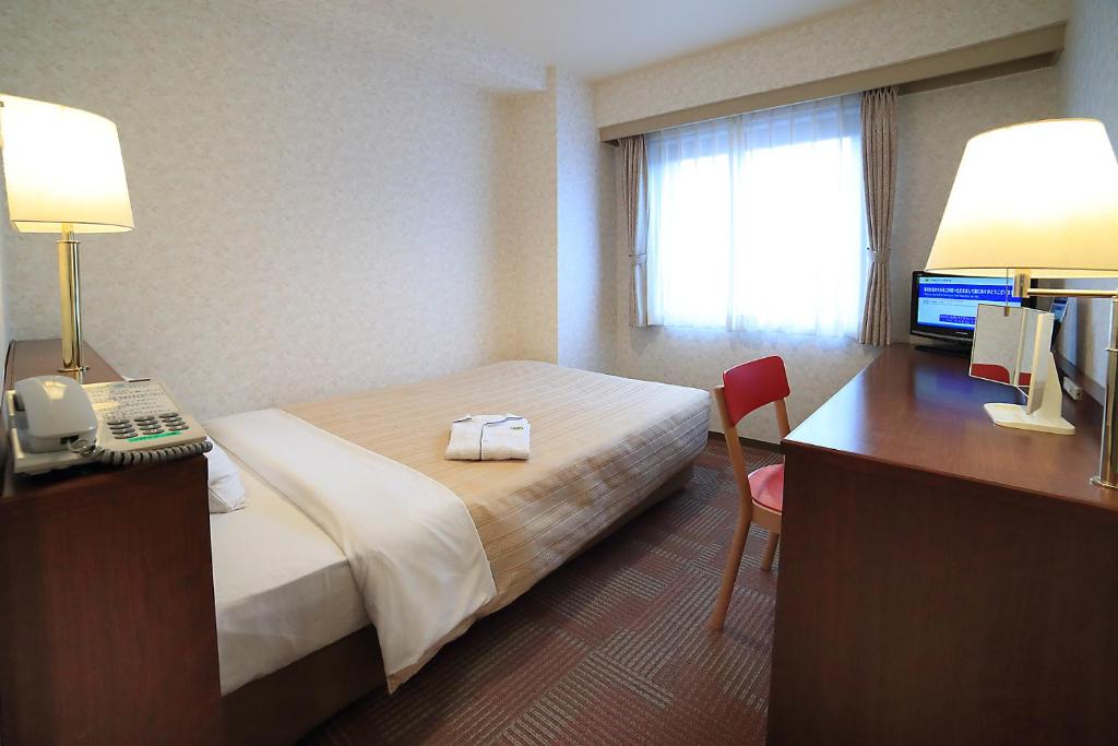 Postel nebo postele na pokoji v ubytování Kumegawa Wing Hotel
