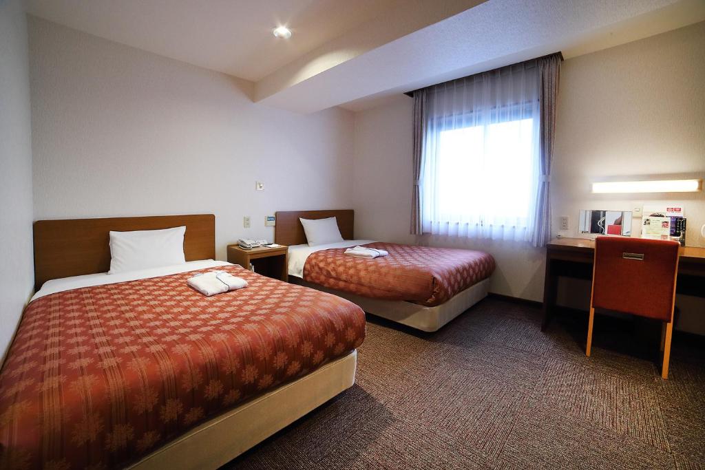 Postel nebo postele na pokoji v ubytování Kumegawa Wing Hotel